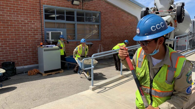 Workers in safety gear collaborate on a clean energy project outside a facility, promoting community engagement in sustainability.