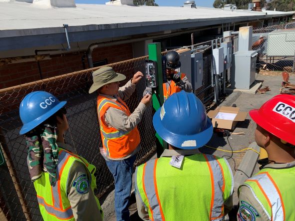 Workers in safety gear observe as an instructor demonstrates electrical installation at a clean energy training session.