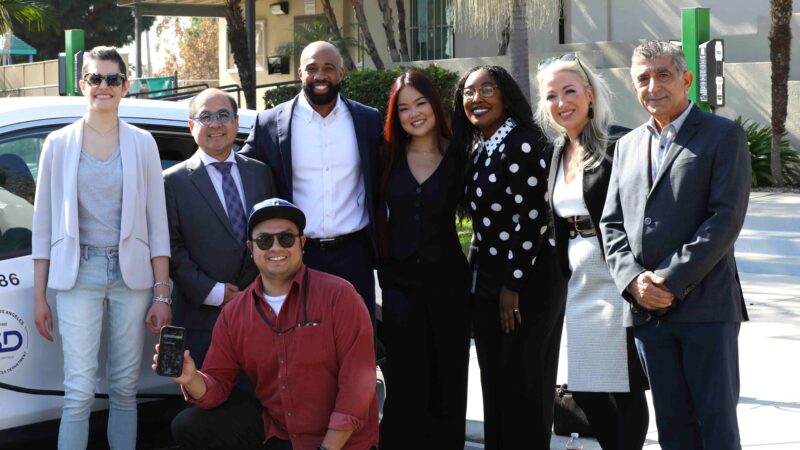 Group of community members and leaders gathered at a clean transportation event, promoting electric vehicle initiatives.