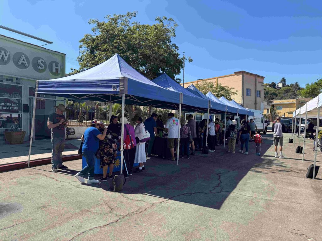 Community members engaging at a local event under tents, fostering connections and promoting clean transportation initiatives.