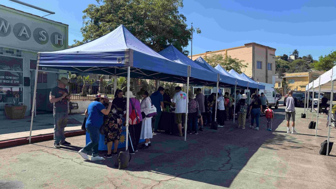 Community members engaging at a local event under tents, fostering connections and promoting clean transportation initiatives.